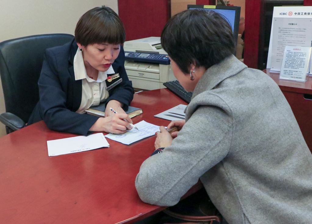 在中国工商银行新疆乌鲁木齐的一处营业网点，李鹏（左）为客户解答问题（2018年11月摄）。新华社发