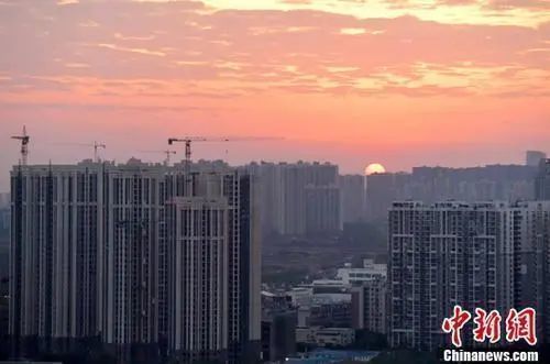 资料图：城区一角，太阳正从东方升起。中新社记者 刘忠俊 摄