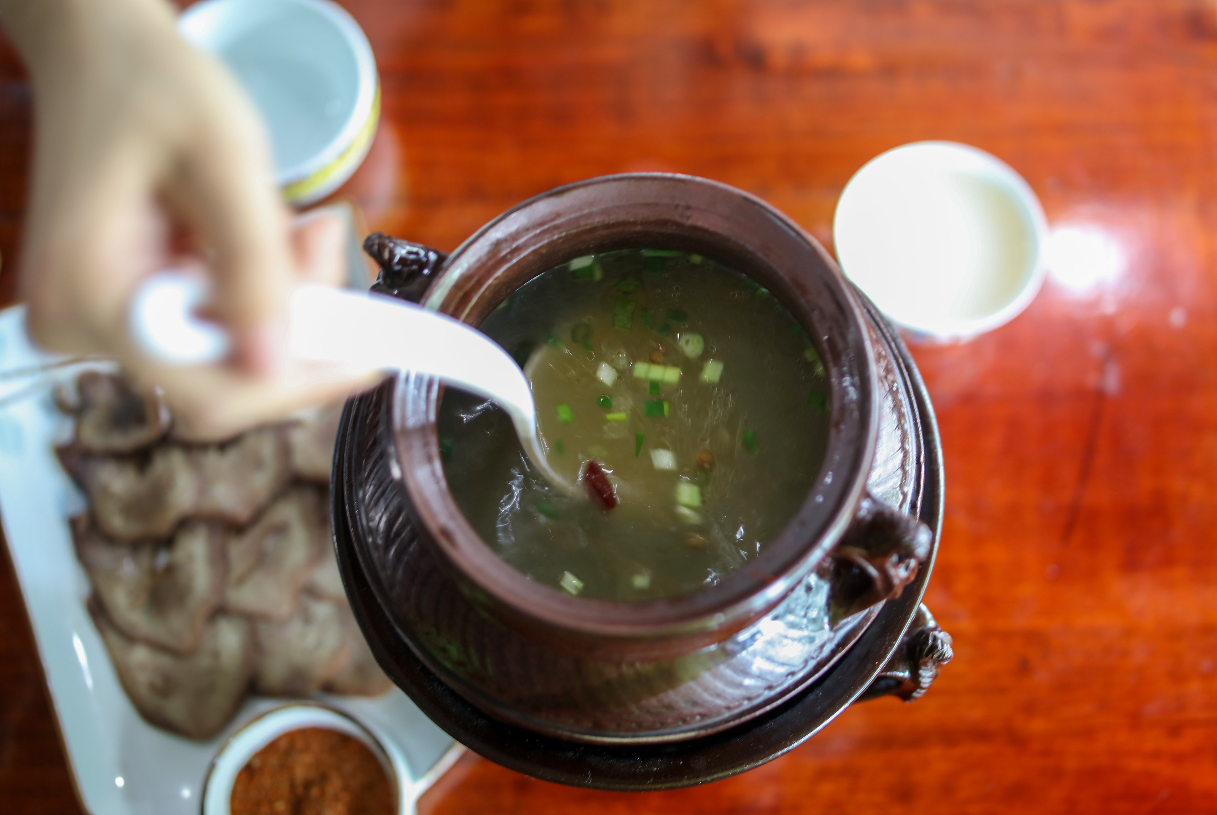顾客在洛桑益西的餐馆里从塔巴陶器罐子里盛汤（7月11日摄）。新华社记者 姜帆 摄