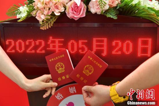 图为情侣在氛围墙前晒出刚领到的结婚证.