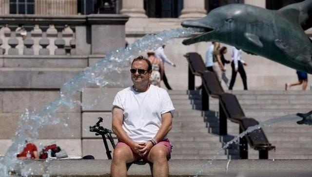 一名男子在英国伦敦的喷泉中泡脚降温。