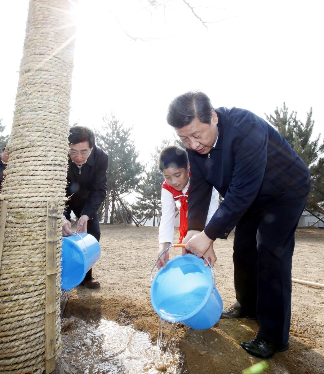 2013年4月2日，習近平等黨和國家領導人來到北京市豐臺區永定河畔參加首都義務植樹活動。這是習近平同少先隊員一起給剛栽下的銀杏樹澆水。新華社記者 鞠鵬 攝