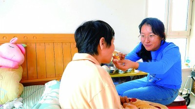 刘羲檬(右)给妈妈喂饭。孙阳摄/光明图片
