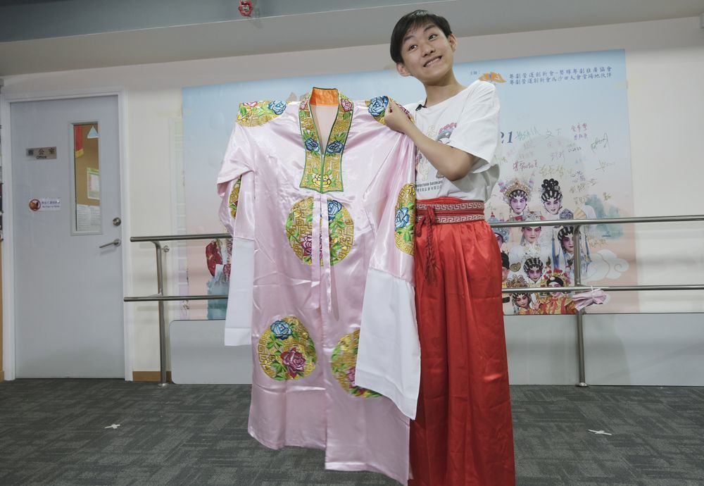 香港粤剧小演员利文喆展示当年给习爷爷表演时穿的戏服，一件粉色底上绣有红蓝色团花的披风（5月29日摄）。新华社记者王申 摄