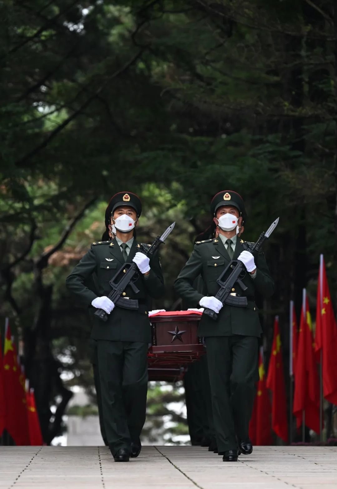 礼兵将烈士棺椁由准备区护送至仪式现场。
