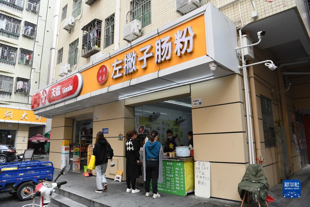 2月12日,深圳市龙华区民治街道水尾村居民在陈用发开的左撇子肠粉店买早餐。新华社记者 梁旭 摄