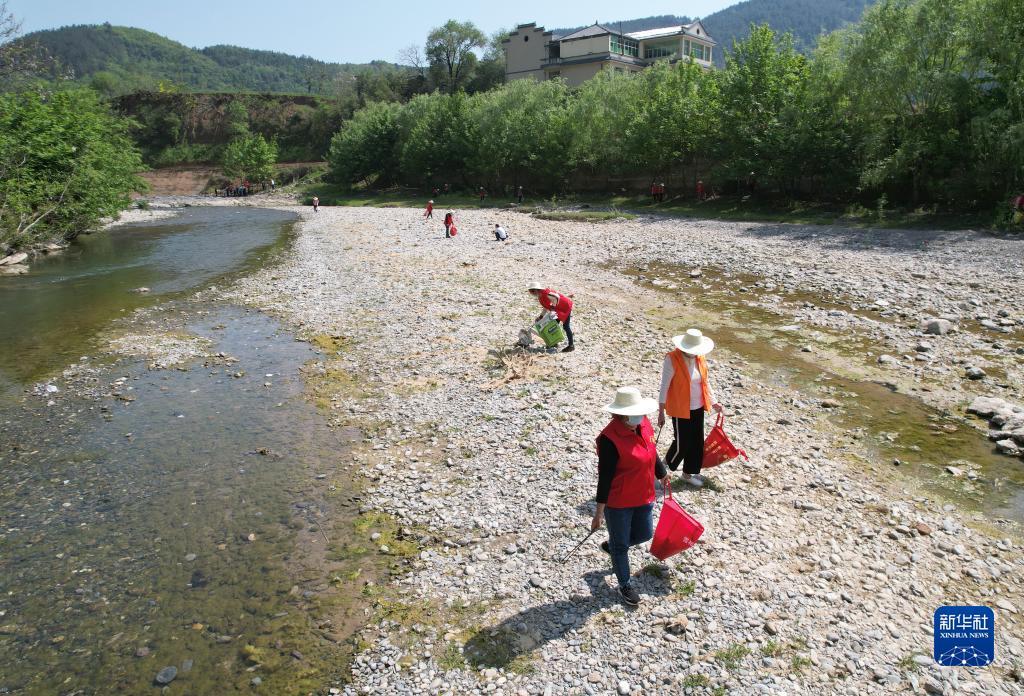 4月10日，女子志愿护河队队员在陕西省旬阳市双河镇高坪社区河边捡拾垃圾（无人机照片）。 新华社记者 邵瑞 摄