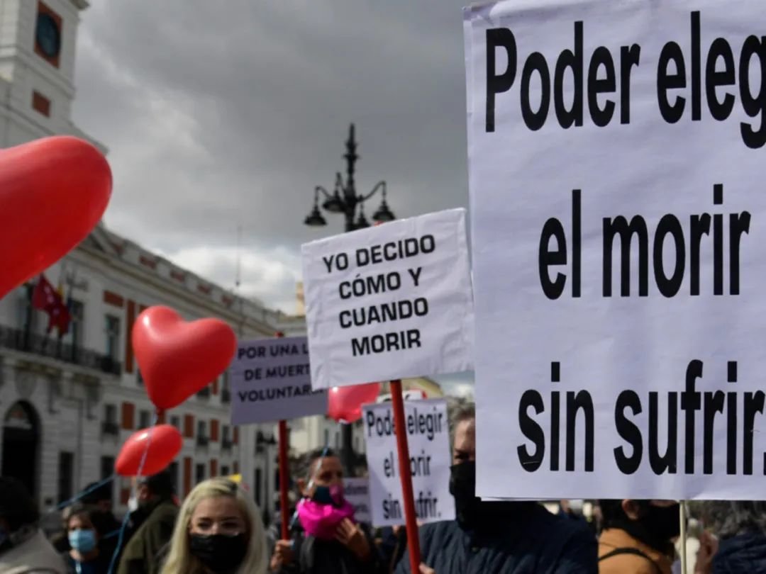 ▲ 2021 年 3 月 18 日，在马德里举行的支持安乐死合法化法律的示威活动中，标语牌上写着“选择死亡而不遭受痛苦”和“我决定何时以及如何死亡”。(法新社图）