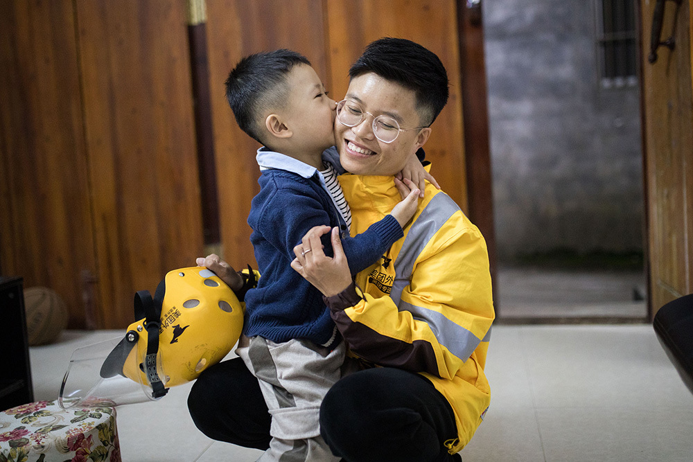 2020年10月28日，广西靖西，一名外卖女骑手回到家中，儿子冲上前亲吻了妈妈的脸颊。许康平/视觉中国 资料图