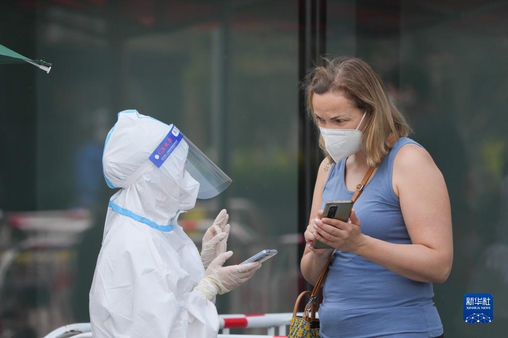  在北京市朝阳区建外街道一处核酸检测点，一位志愿者（左）为外籍人士核对身份信息（5月5日摄）。 新华社记者 鞠焕宗 摄