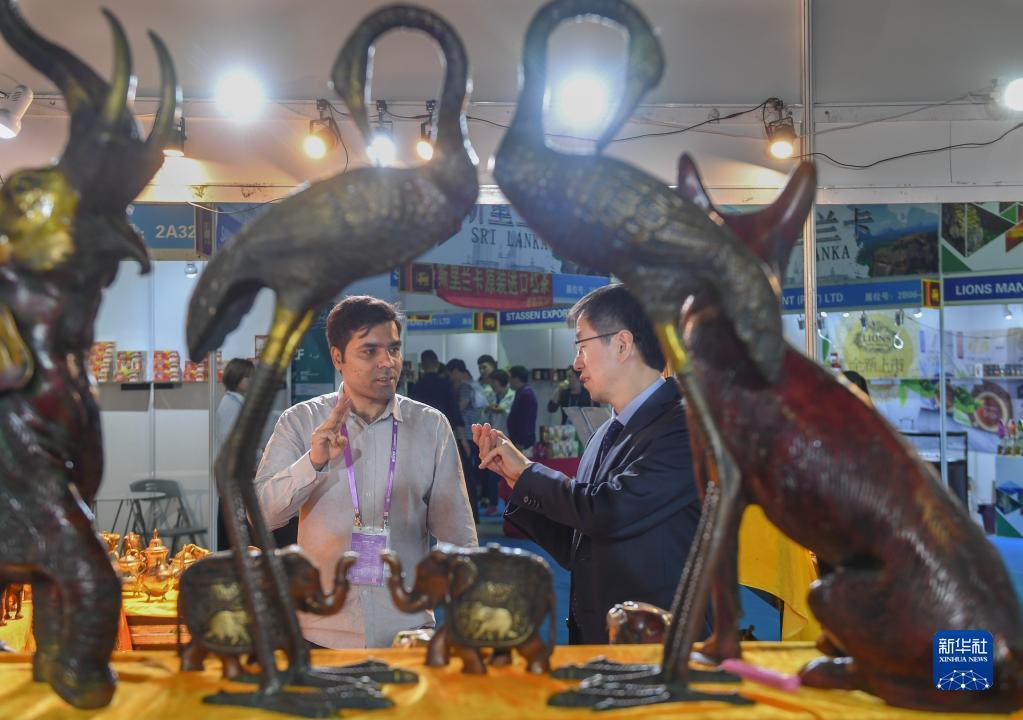 2019年4月18日，在福建泉州石狮市举行的第五届中国（泉州）海上丝绸之路国际品牌博览会上，印度客商（左）向顾客推销印度工艺品。 新华社记者 宋为伟 摄