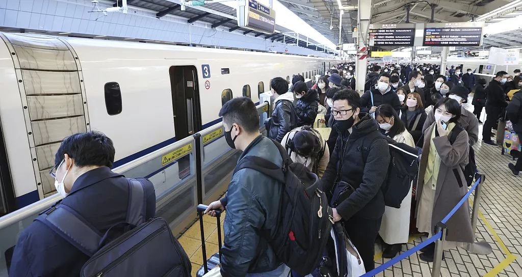 当地时间2022年12月29日,日本东京站,携带大件行李的乘客在新干线高铁站台上。图/视觉中国