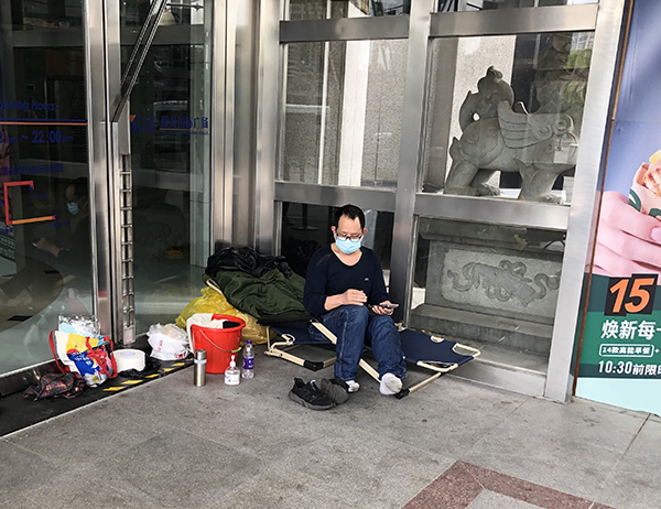 西藏南路，亚龙国际一楼出入口的玻璃隔间内，唐全睡在一张躺椅上。