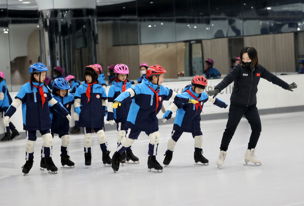 在上海新世界城的冰雪乐园，黄浦区卢湾一中心小学的学生在教练的指导下练习滑冰（2021年12月22日摄）。新华社记者 刘颖 摄