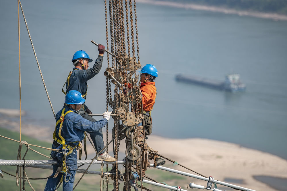 ↑9月13日，工人在白鹤滩-浙江±800千伏特高压直流输电线路工程（重庆段）江津长江大跨越施工现场作业。