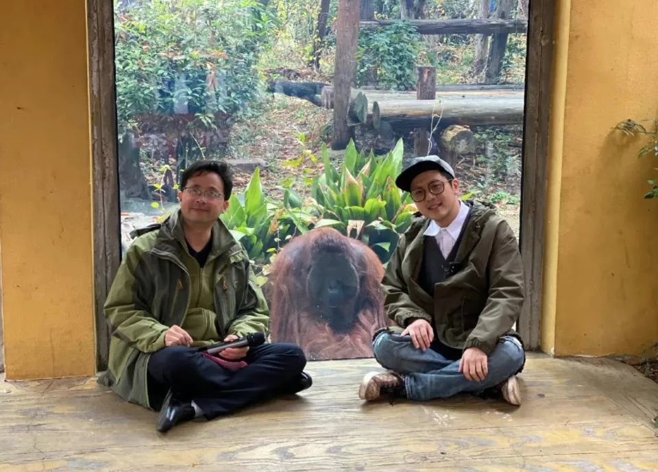 红山森林动物园园长沈志军（左）盘腿坐地上给认养仪式致辞。