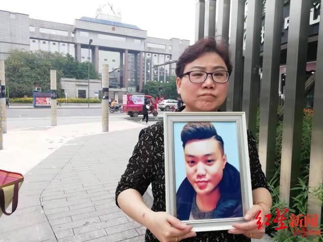 ↑母亲陈晔抱着儿子的遗像 （资料图）