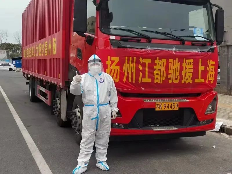 龚栋李与挂有“扬州蛋炒饭为上海生煎包加油”标语的大货车