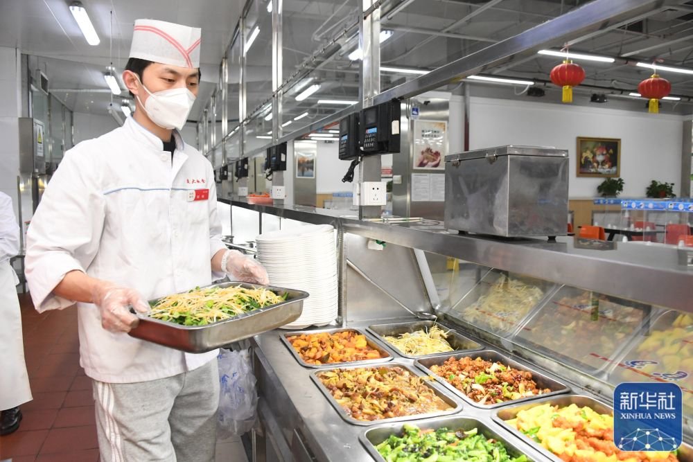 1月21日,在北京交通大学学苑餐厅,工作人员将制作好的午餐放入窗口。新华社记者 任超 摄