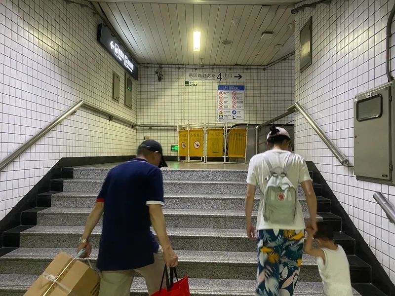 地铁站里，一处自动扶梯处于检修状态，乘客只能拖着重物走楼梯 摄影/佟鑫