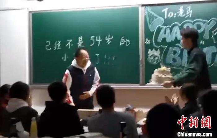 学生捧上点燃蜡烛的生日蛋糕,让马老师许愿。 徐州市树恩高级中学供图