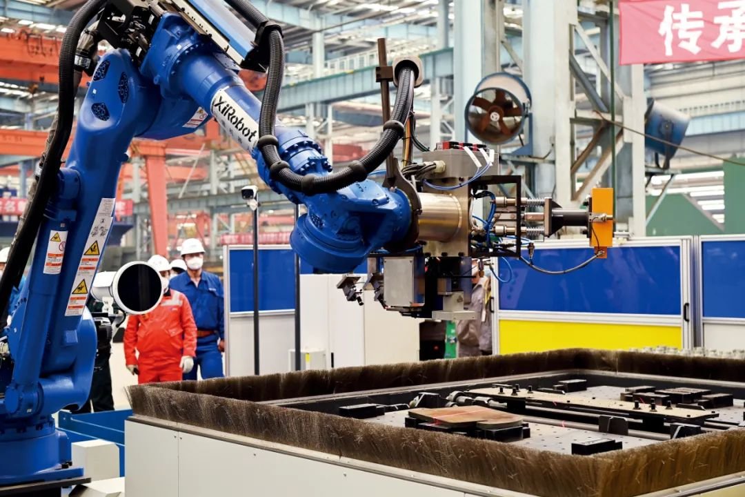 江南造船的吊马智能工作站里,机器人正在进行焊接。据介绍,这个智能工作站中,除装配工序外,搬运、焊接、打磨、下料等工序全部由机器人完成,首次在船舶行业内集成了机器人视觉识别、智能抓取、智能焊接技术,是目前行业内最先进的船用吊马生产线,它的投入使用将大大减少人工需求,将原来的27人团队压缩至5人,且能够保持吊马生产质量的稳定性。图/江南造船集团提供