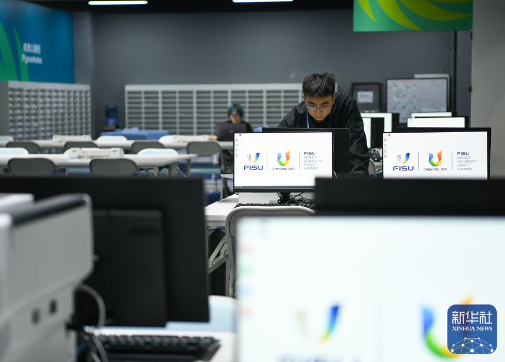 ↑ 7月13日,在成都大运会主媒体中心,工作人员正在调试媒体工作间的电脑。新华社记者 王曦 摄