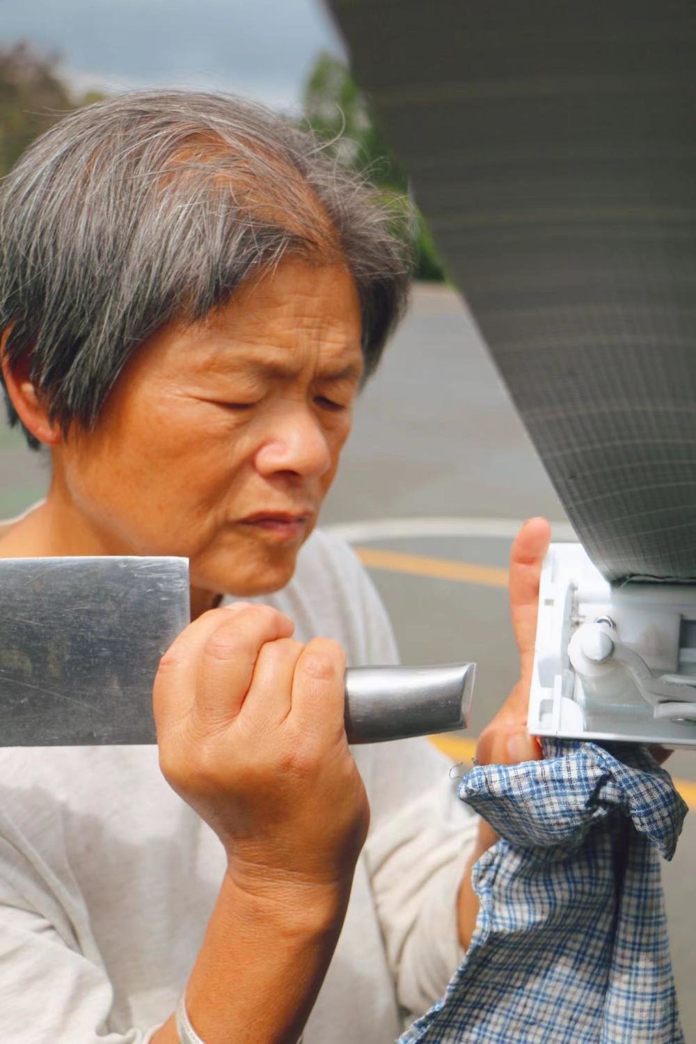 下了一夜的雨,遮阳架因承受不住重量损坏,张瀛正尝试用菜刀柄修理。朱雅文 摄