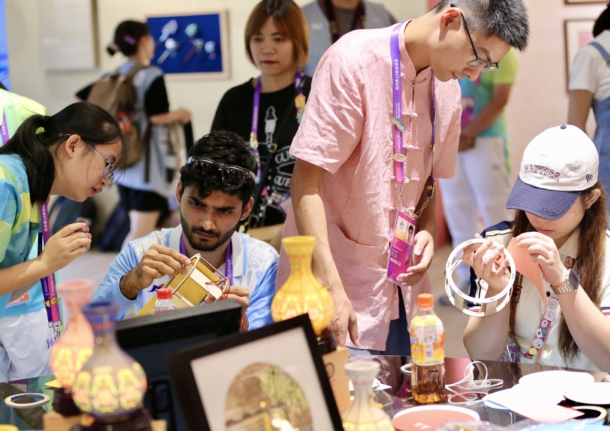 9月29日，中国香港运动员朱咏翘（右一），印度运动员希瓦&middot;纳尔瓦尔（左二）制作硖石灯彩。中国日报记者 张威 摄