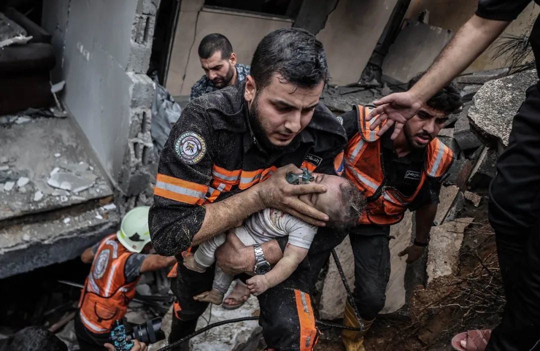 当地时间2023年10月9日，加沙城，以色列空袭后，巴勒斯坦救援队废墟中抢救6个月大婴儿Sema al-Misri（视觉中国 供图）
