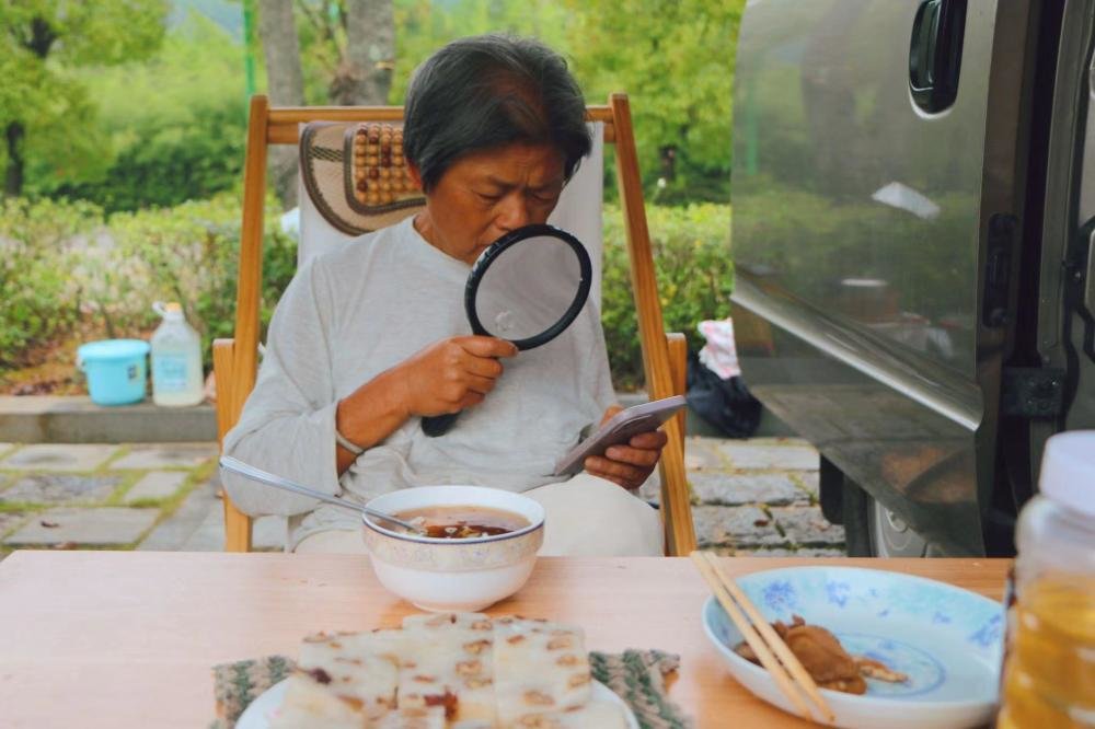 张瀛不习惯戴老花镜,经常用放大镜浏览手机。朱雅文 摄