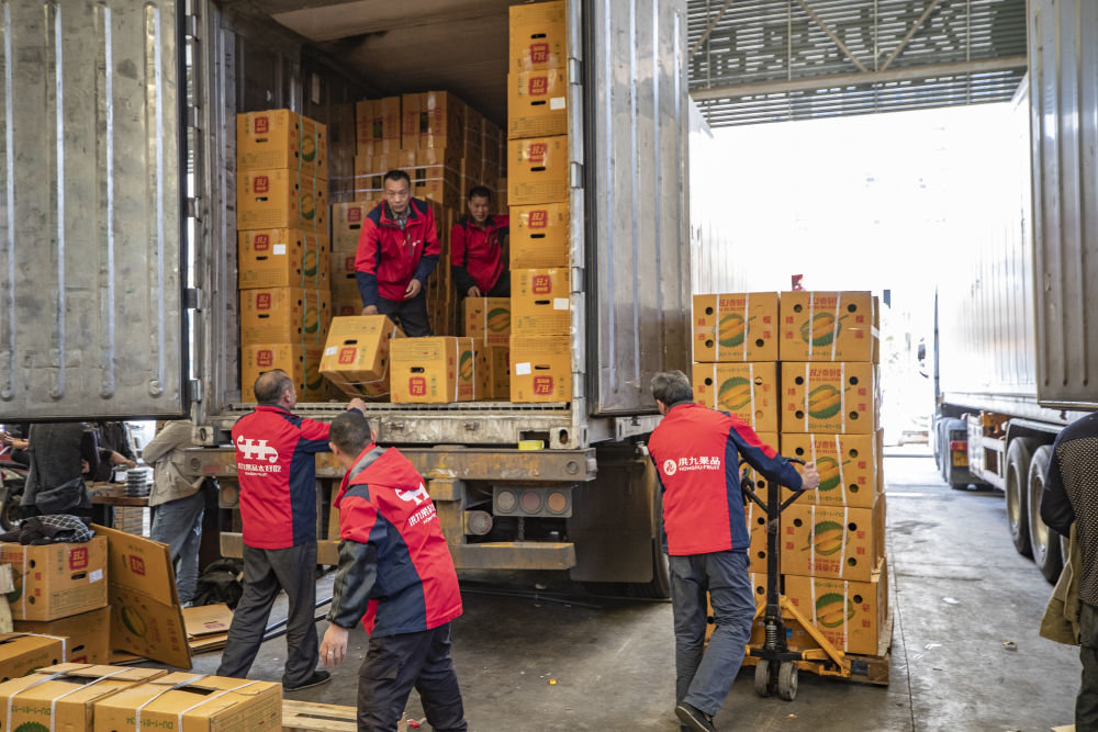 在重庆市江津区双福农贸城,洪九果品的工作人员在搬运从泰国运输过来的榴莲(2022年4月19日摄)。新华社记者 黄伟 摄