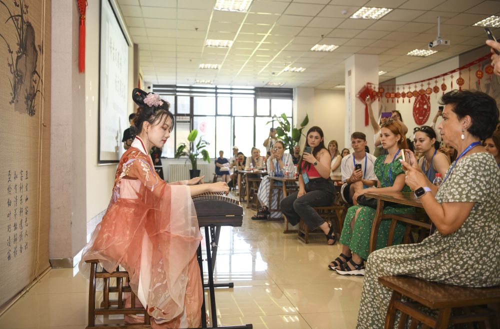 在新疆图书馆,乌鲁木齐古筝爱好者为国外歌舞团演员演奏《渔舟唱晚》(7月23日摄)。新华社记者 胡虎虎 摄