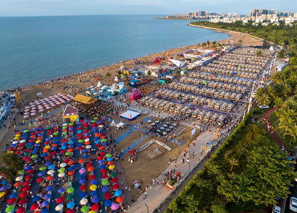 2023年6月10日晚，坐落于海南省海口市白沙门沙滩的海口白沙门文创市集开市。该市集面积达6万平方米，包含音乐餐吧区、文创工艺区、小吃餐饮区、酒吧区、自由演绎区等业态区域，聚集超700个国内外餐饮、文创商家，集夜游、夜购、夜娱为一体。图为民众在海口白沙门文创市集购买特色小吃。中新社记者 骆云飞 摄 　 　