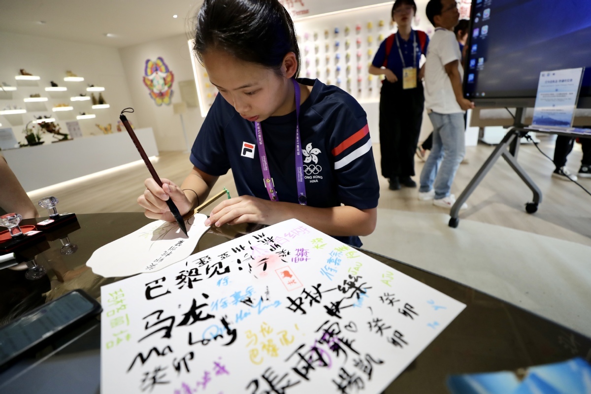 9月29日，中国香港运动员杨凯晴在团扇上写毛笔字。中国日报记者 张威 摄