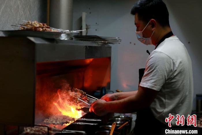 工作人员正在翻烤肉串。 梁犇 摄