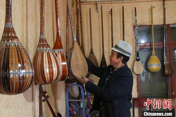 10月15日,新疆阿克苏地区新和县依其艾日克镇加依村乐器制作匠人努尔冬·司马义在检查手工制作的乐器。苟继鹏 摄