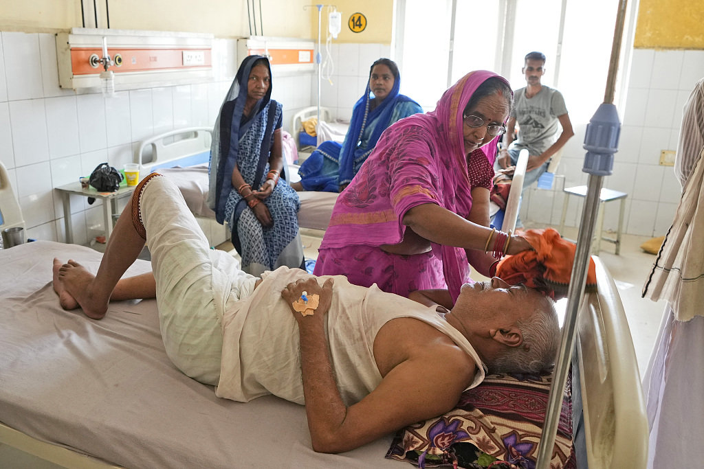 当地时间2023年6月19日，印度北方邦，巴利亚地区医院，一名妇女给生病的丈夫擦头。