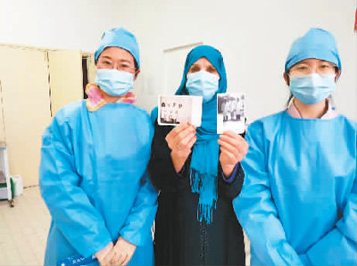 一名当地退休护士（中）展示27年前与中国援阿尔及利亚医疗队的合影。