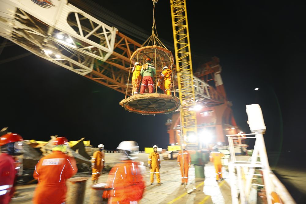 12月17日，在渤海海上平台作业海域，建设者乘吊笼上运输船准备前往施工现场。