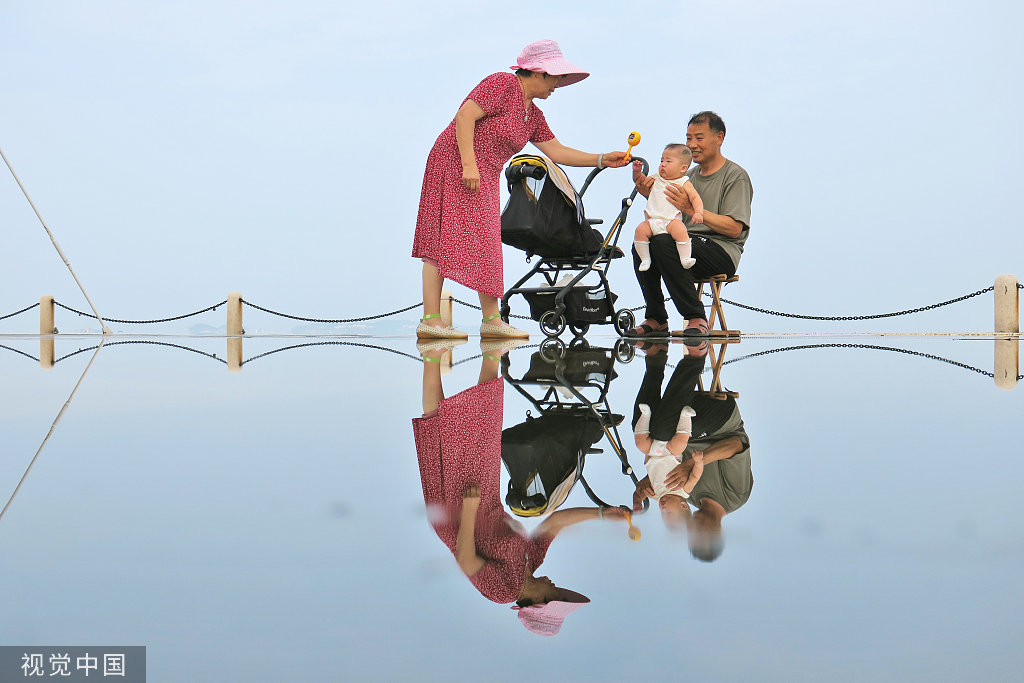 2022年7月29日,山东烟台,一对老年夫妇正在逗弄孙辈。(视觉中国)