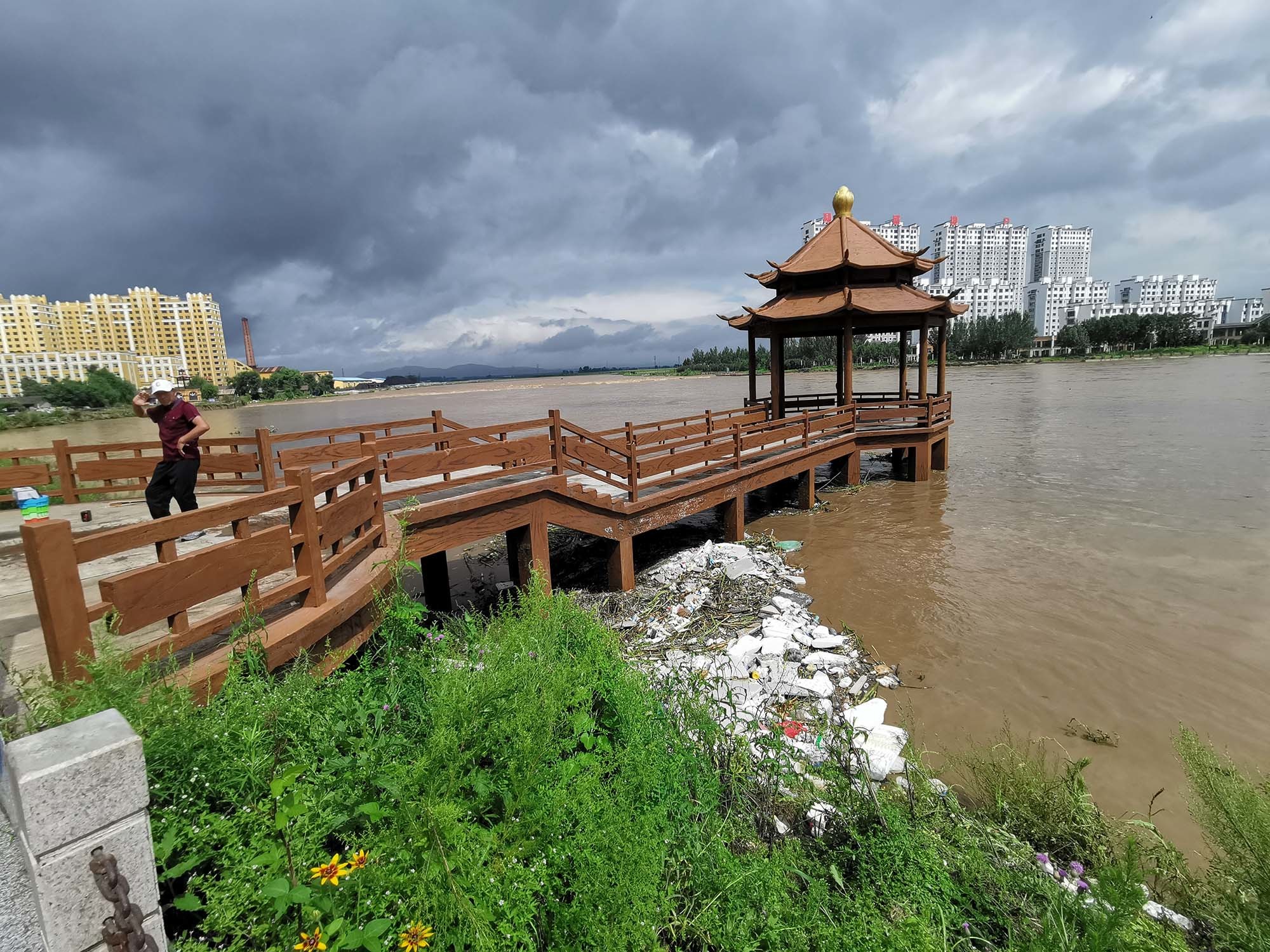 8月5日上午，尚志市一位市民在蚂蚁河边跳舞。河对岸地势较低，蚂蚁河涨水时，那里有部分小区进水被淹。