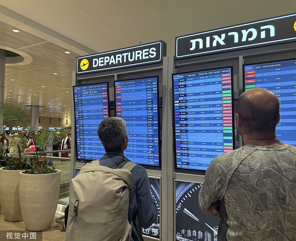 当地时间2023年10月8日，以色列特拉维夫，由于“哈马斯”在当地发动袭击，许多来自国外的航班被取消，人们看着以色列唯一的国际机场本古里安机场的起飞时间表。 视觉中国 图