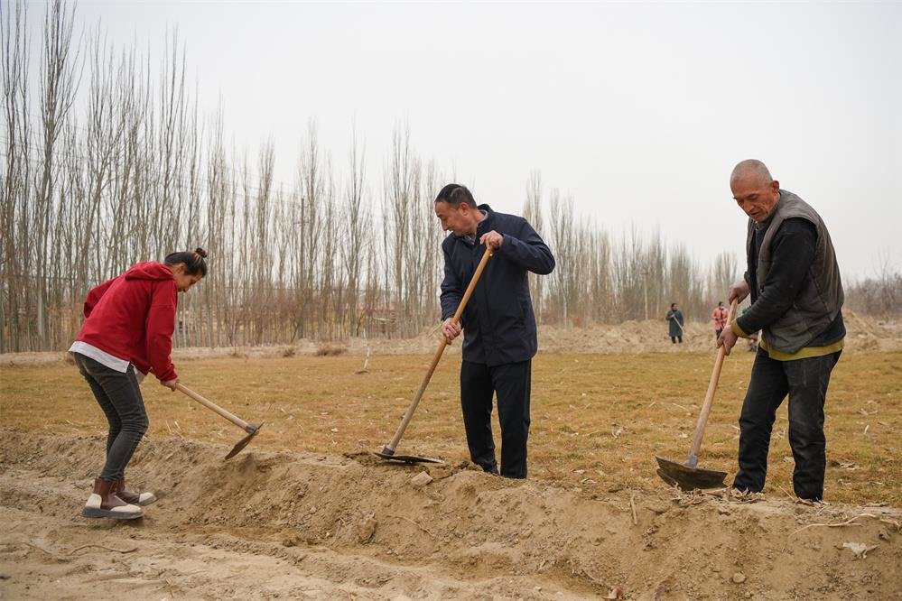 2月20日，在新疆和田地区策勒县巴什玉吉买村，买买提依布热依木·买买提明（中）和村民一起整理土地，为春耕生产做准备。新华社记者 丁磊 摄
