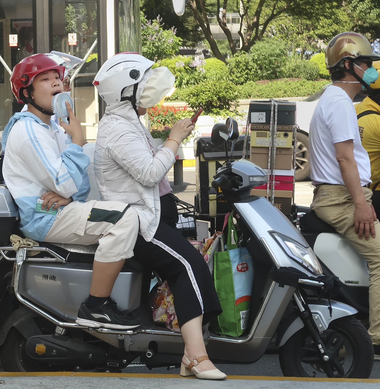 2023年6月28日，上海，徐家汇街头，烈日下的市民用小电扇驱热。