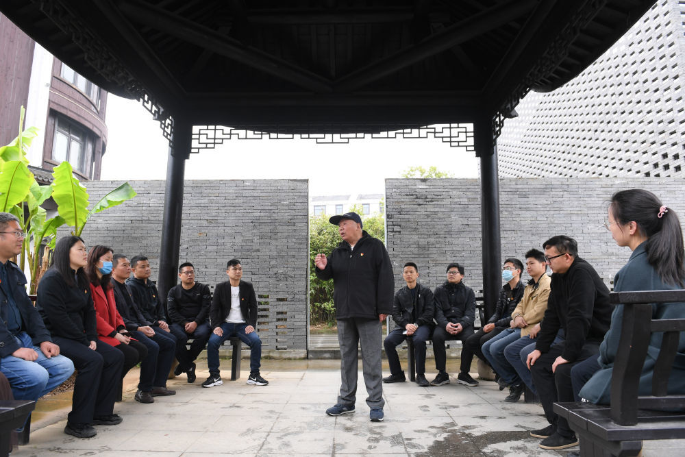 浙江绍兴诸暨市枫桥镇魏廉村老党员魏杏根（中）在枫桥经验陈列馆的亭子内和年轻党员分享当年运用“枫桥经验”化解基层矛盾的故事（2021年4月11日摄）。