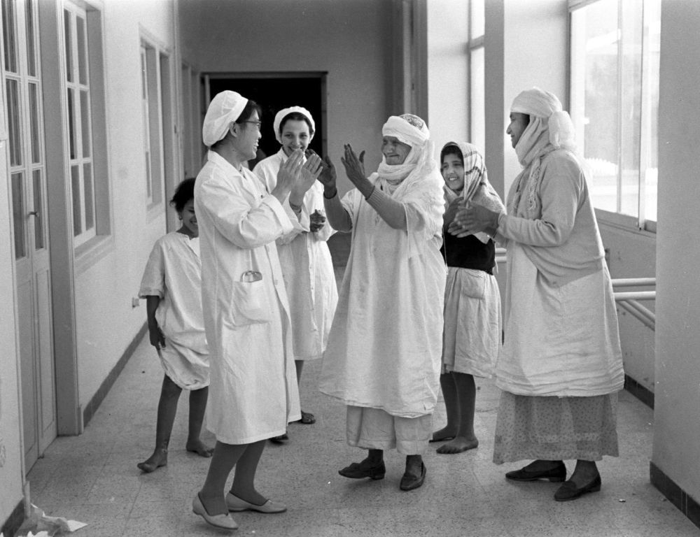 ↑1966年5月，在阿尔及利亚西部的玛斯卡拉，两位经过中国医生医治后重见光明的患者和中国女医生一起拍手欢呼。新华社记者 孙星文 摄