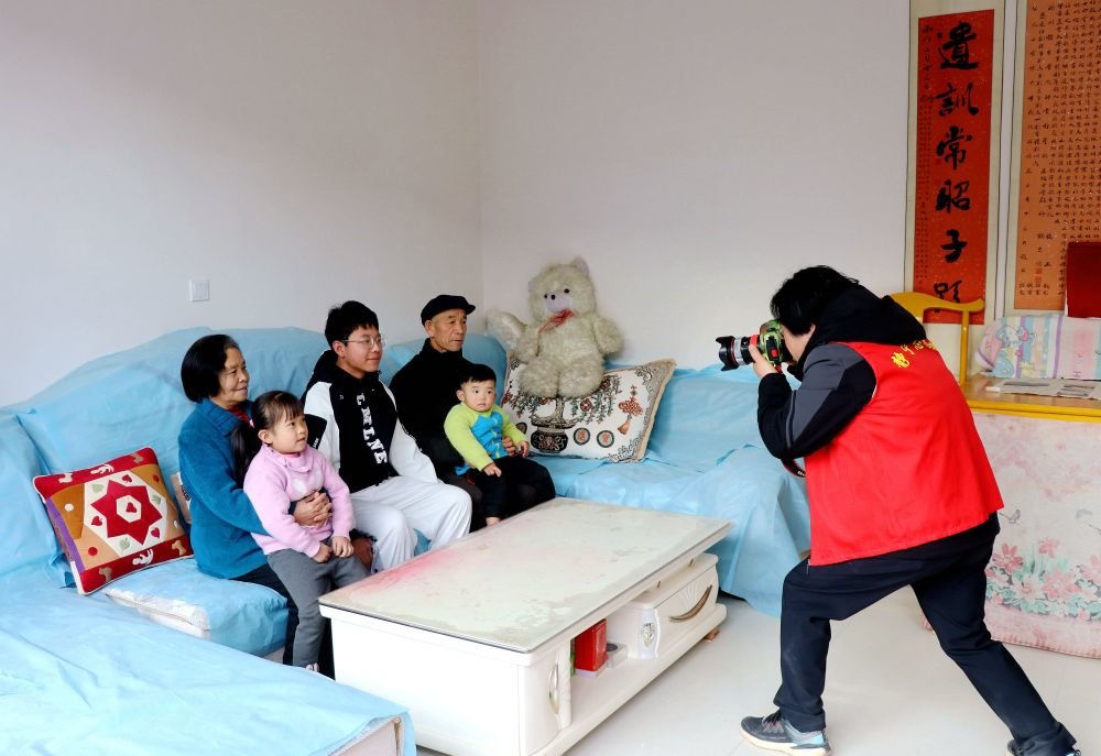 1月9日,在甘肃省平凉市静宁县威戎镇杨湾村,一名志愿者在给村民