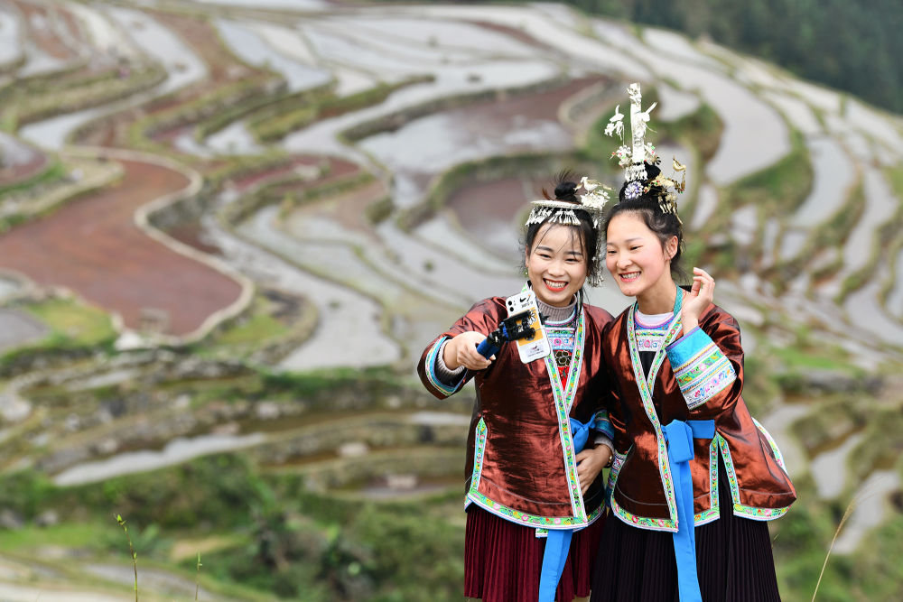 ↑在贵州省从江县加榜乡，扶贫网格员吴贤艳（左）与村里的大学生梁琼英直播推介加榜梯田风光（2020年4月19日摄）。