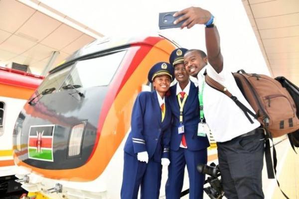 2017年5月31日蒙内铁路通车，图为蒙巴萨西站，一名肯尼亚记者（右一）和火车司机肯西莉亚（中）合影留念。图|新华社孙瑞博